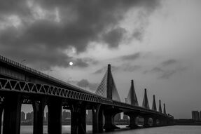 Фотообои Висящая над мостом луна через облака